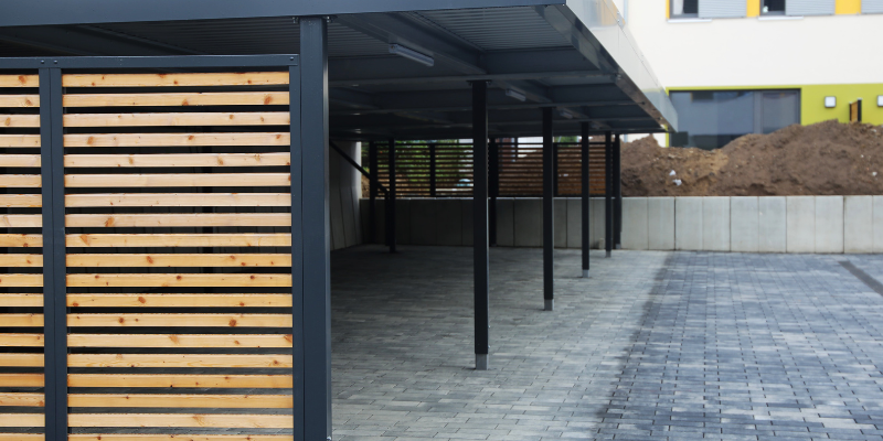 Covered carport in Dubai Hills with black metal structure and privacy screening made of wooden slats