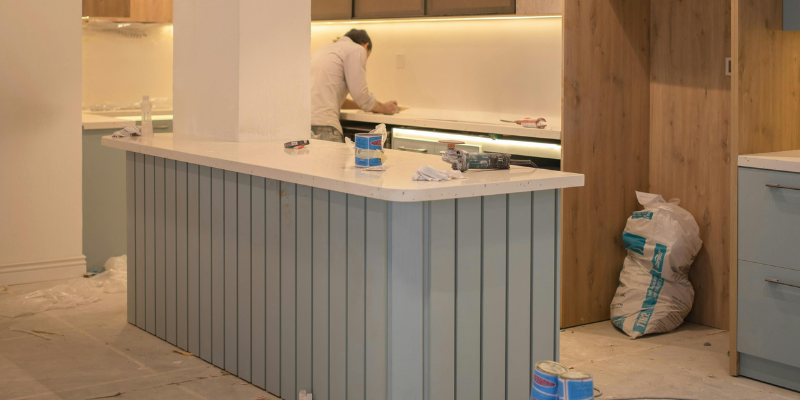 Partially completed luxury kitchen renovation in Dubai with new island installation, tile flooring, and construction materials